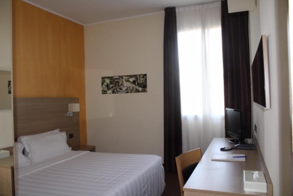 1 dormitorio con 1 cama y escritorio con TV en Hotel First, en Calenzano