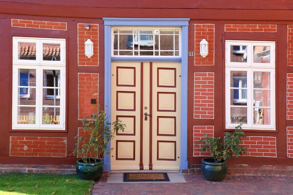 ブレッケーデにあるAlte Schmiede Bleckedeの白いドアと窓のある赤レンガ造りの家