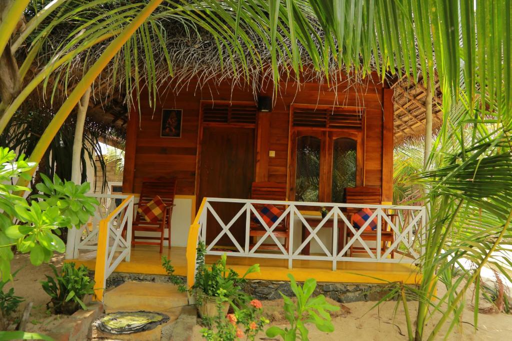 a small wooden house with a porch and a balcony at Gems Garden Guest House in Tangalle