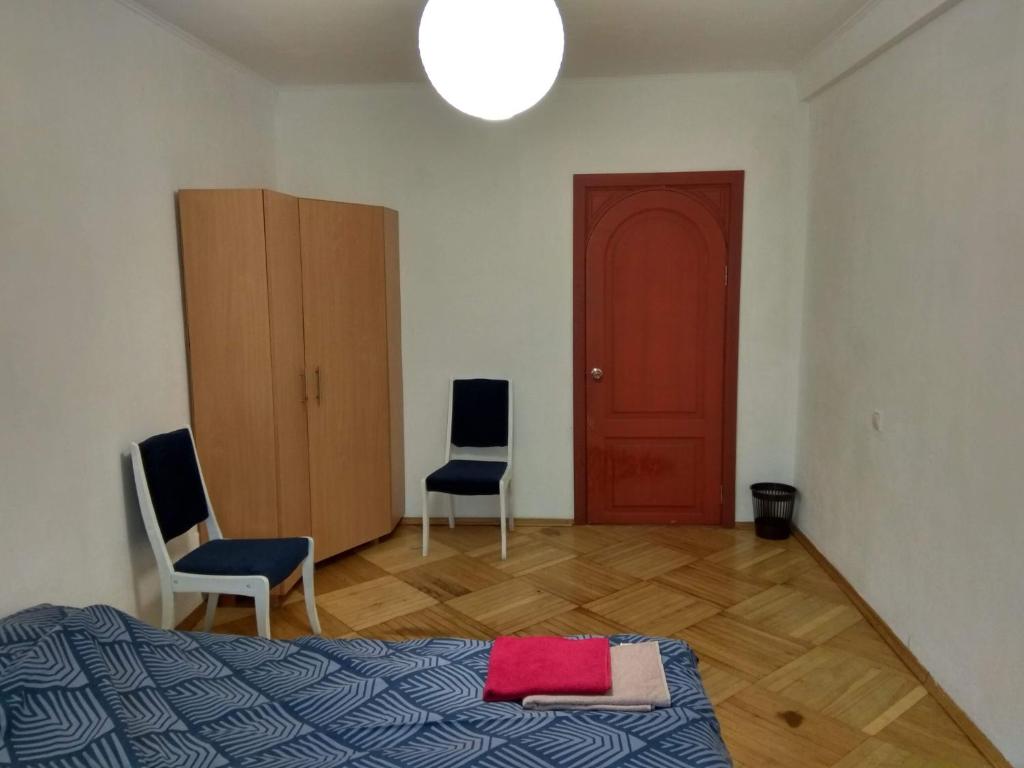1 dormitorio con 2 sillas, 1 cama y puerta roja en Alaska, en Kiev