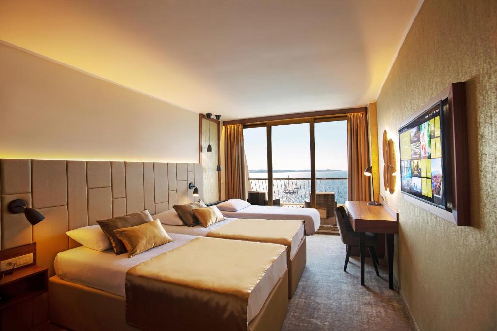 a hotel room with two beds and a desk at Grand Hotel Bernardin in Portorož