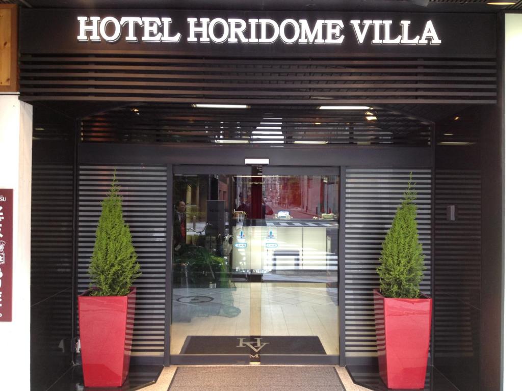 a hotel hollywood villa with two potted plants in front of a door at Hotel Horidome Villa in Tokyo