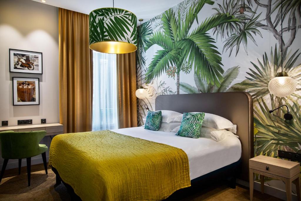 カンヌにあるHotel Verlaineの黄色い毛布付きのベッドが備わるホテルルームです。