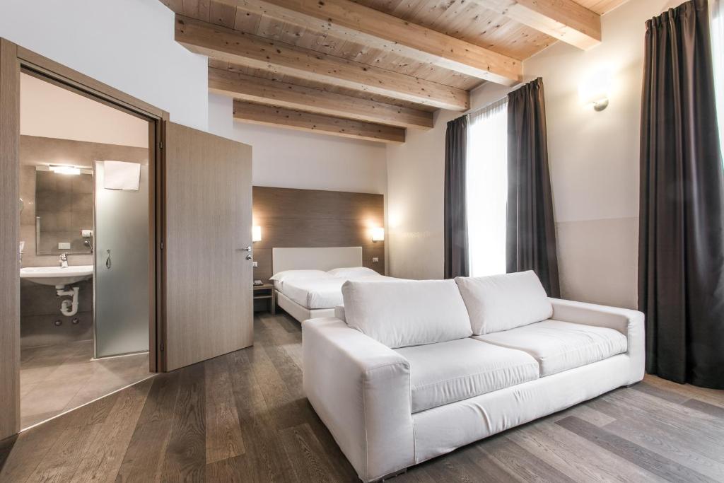 a living room with a white couch and a bedroom at Hotel Operà in Dossobuono