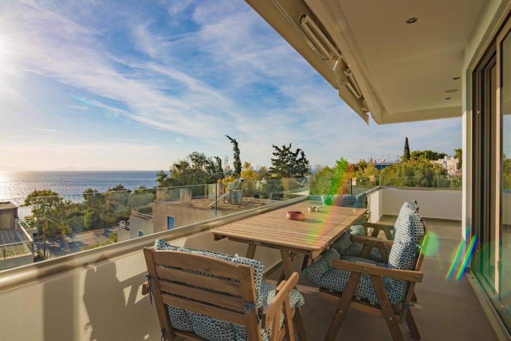 a balcony with a wooden table and chairs and the ocean at Best Seaview Saronida Athens Riviera in Saronida