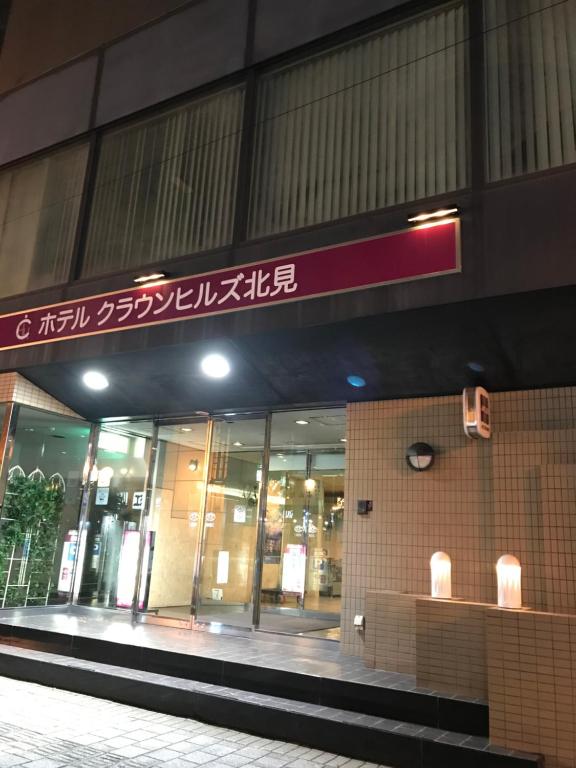 een winkel voor een gebouw met een bord erop bij Hotel Crown Hills Kitami in Kitami