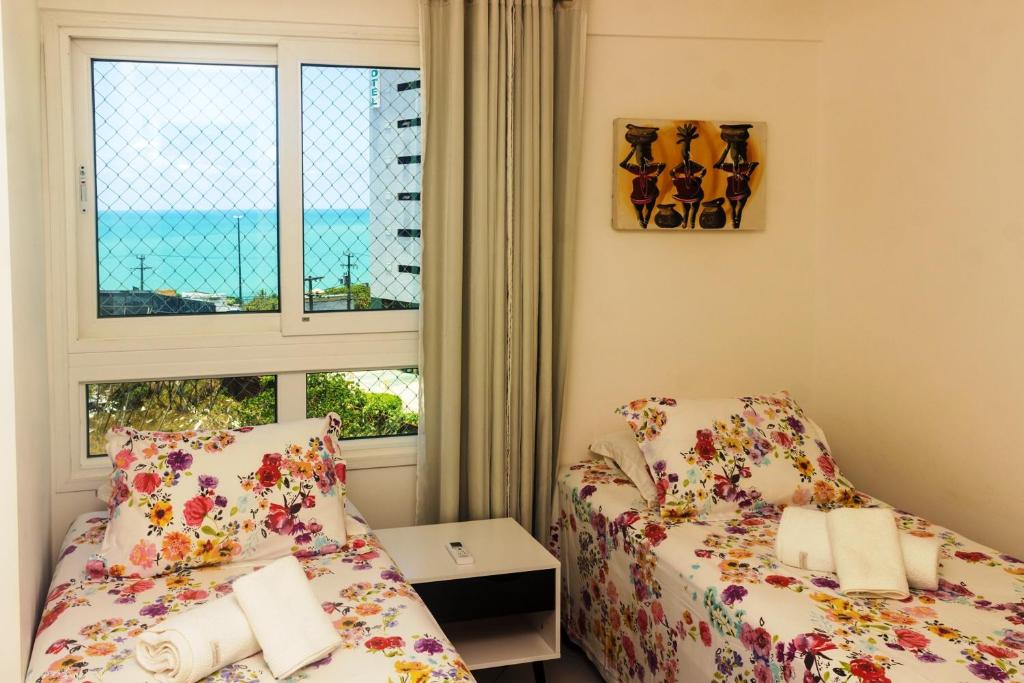 two beds in a room with a window at Marina Bezerril - 304 Pontamares - Pertinho de tudo,mar e restaurantes in Natal