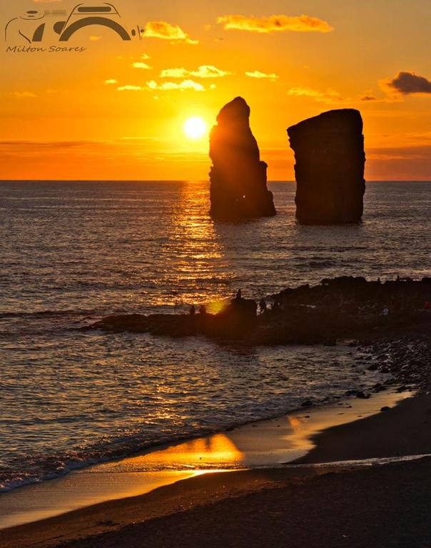 a sunset over the ocean with a rock formation at Casa Dos Mosteiros in Mosteiros