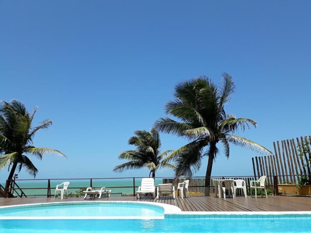 een zwembad met stoelen en palmbomen naast de oceaan bij Atlântico flat 214 in Natal