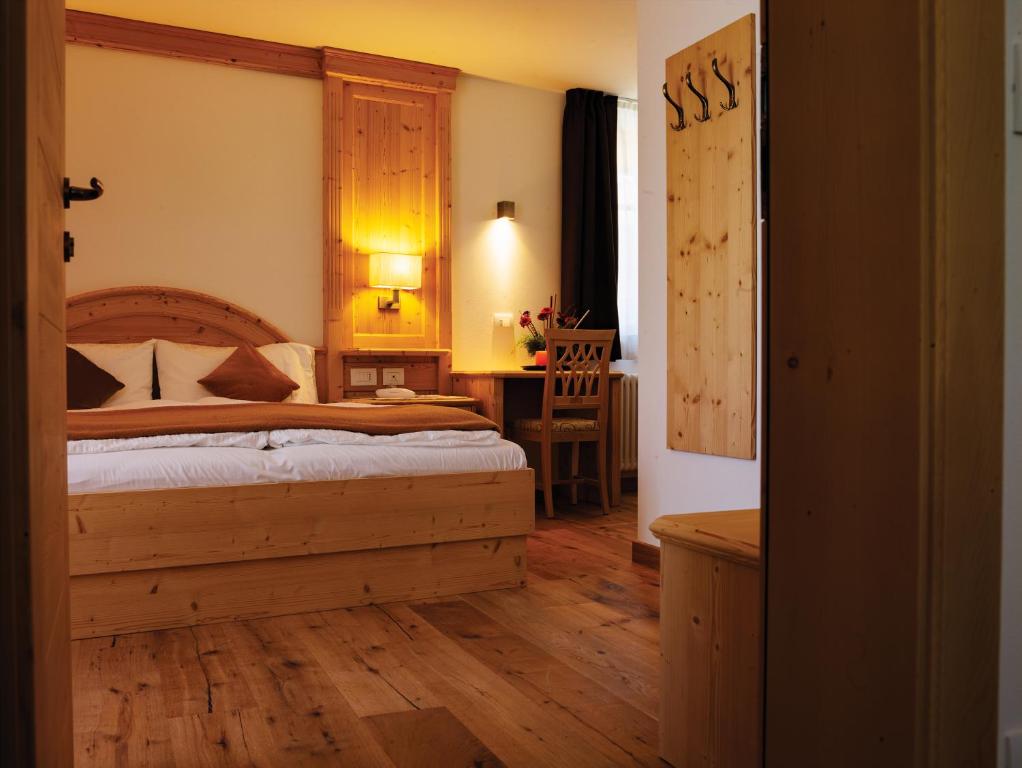 Schlafzimmer mit einem Bett mit einem Kopfteil aus Holz in der Unterkunft Garni Le Maddalene in Coredo