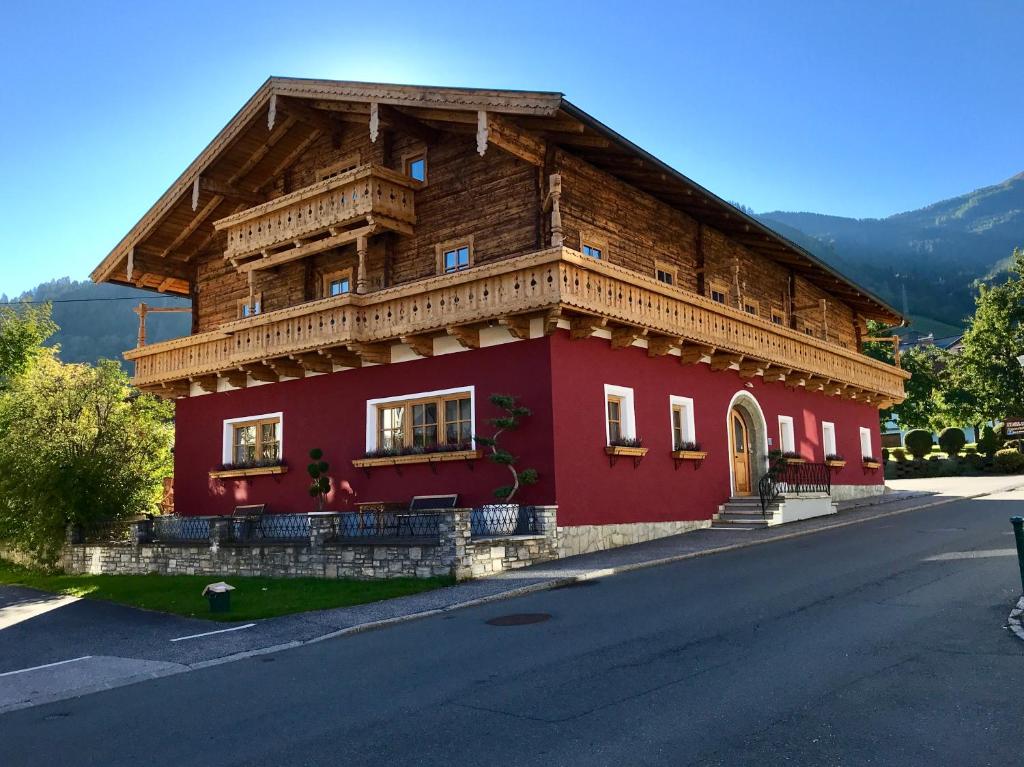 a red house with a wooden roof on a street at APARTMENT SONNBLICK, Kaprun, Salzburg - inklusive Sommerkarte in Kaprun