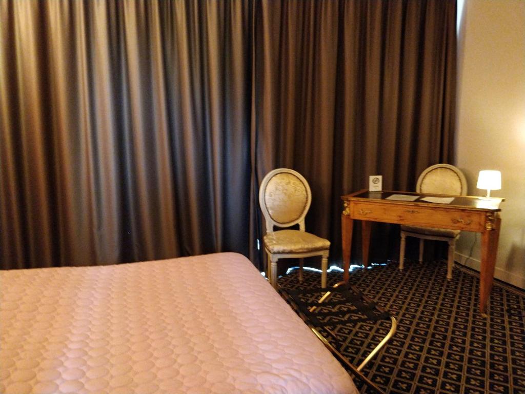 - une chambre avec un lit, un bureau et une table dans l&#39;établissement Hotel Fleur de Lys, à Bailleul