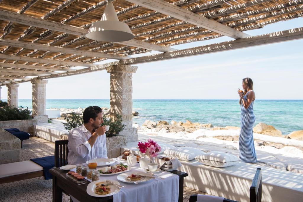 a man and woman sitting at a table on the beach at La Peschiera in Monopoli
