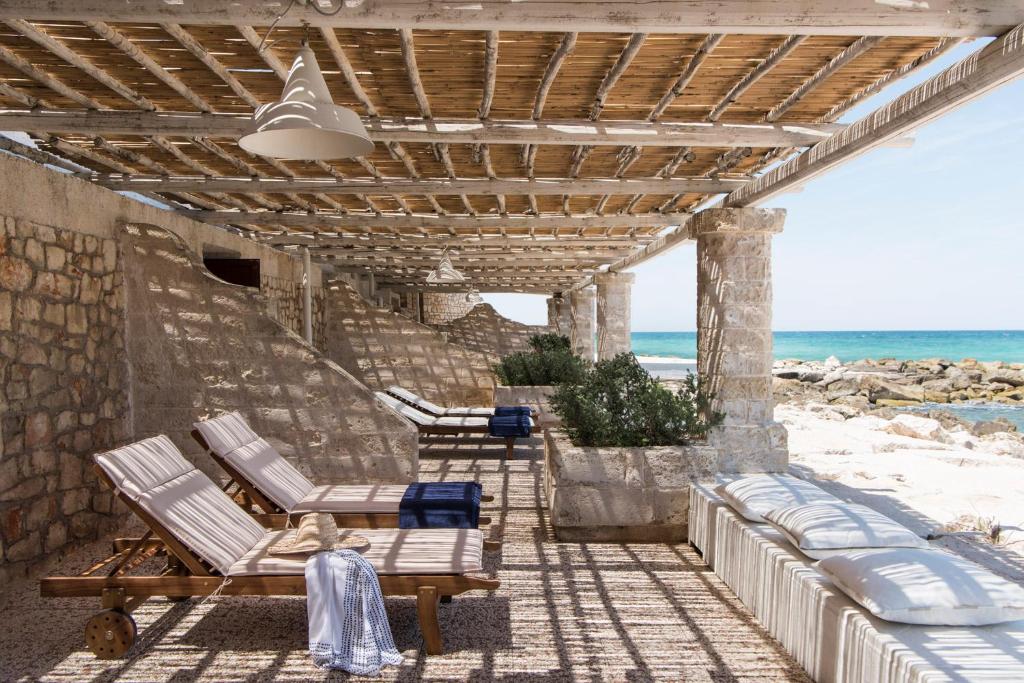 a patio with chaise lounges on the beach at La Peschiera in Monopoli