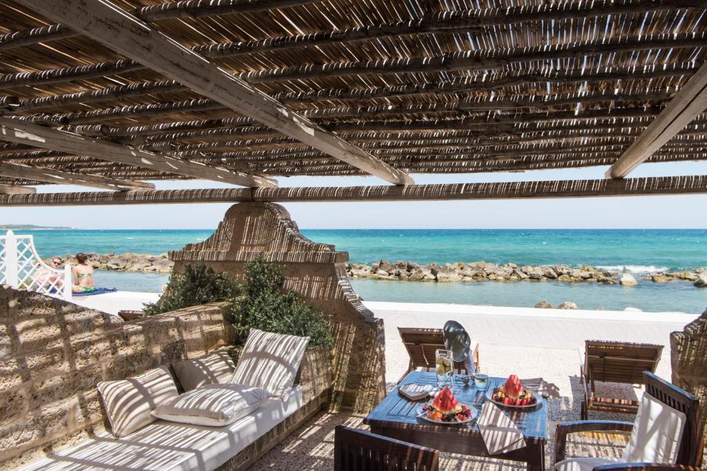 a patio with a table and chairs and the ocean at La Peschiera in Monopoli
