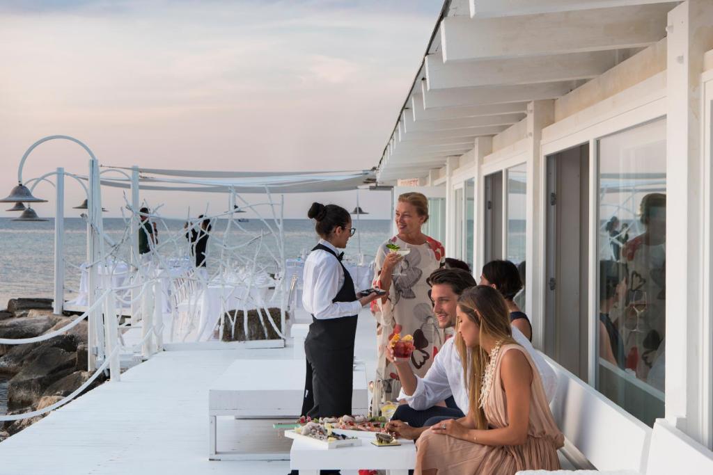 a group of people sitting around a table on a balcony at La Peschiera in Monopoli