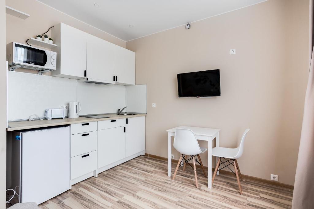 OdintsovoにあるKandinsky Studio 1の白いキャビネット、テーブルと椅子付きのキッチンが備わります。