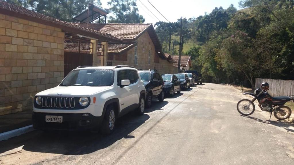 eine Reihe von Autos, die an der Straßenseite geparkt sind in der Unterkunft Pousada Tia Lilía in Gonçalves