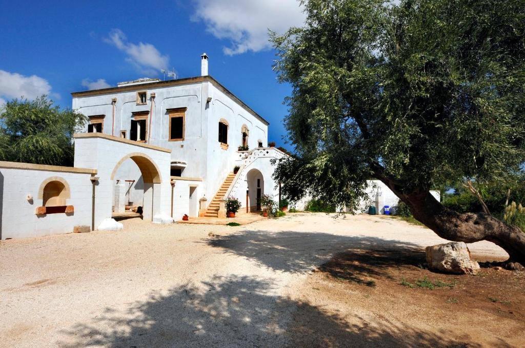 une maison blanche avec un arbre en face dans l'établissement Masseria De Michele, à Montalbano