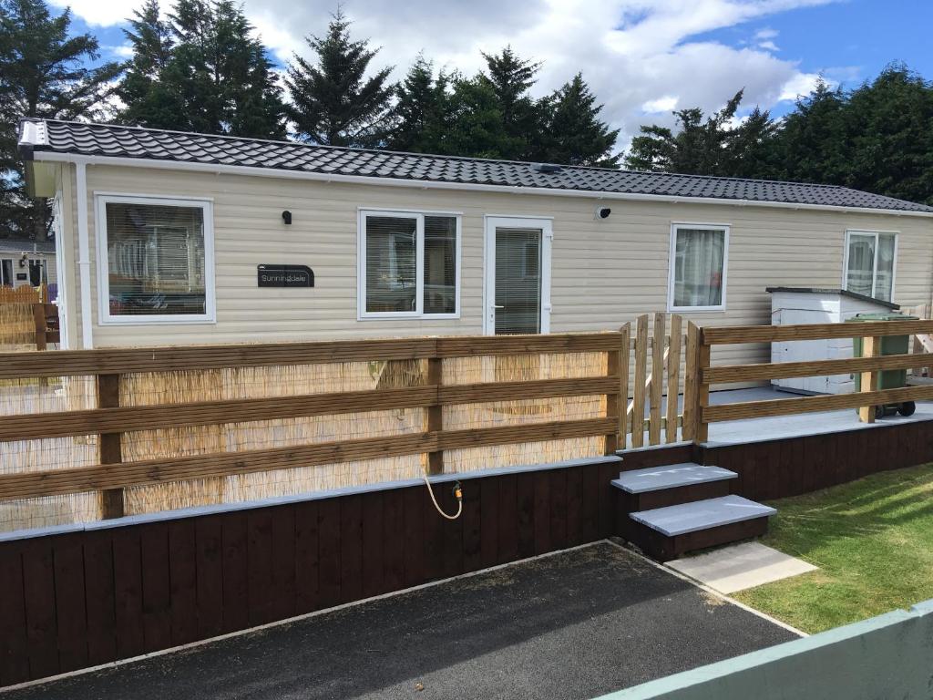 a mobile home with a wooden fence and stairs at The Balmoral Caravan in Dornoch
