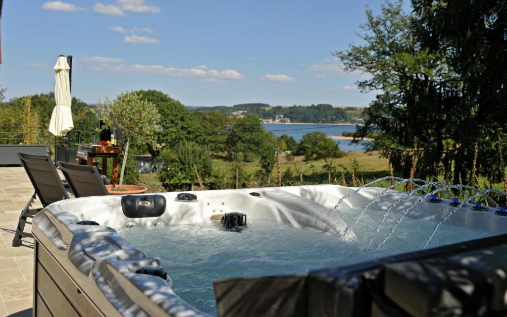 une baignoire jacuzzi avec vue sur le lac dans l'établissement Gites Domaine du Charouzech, à Salles-Curan