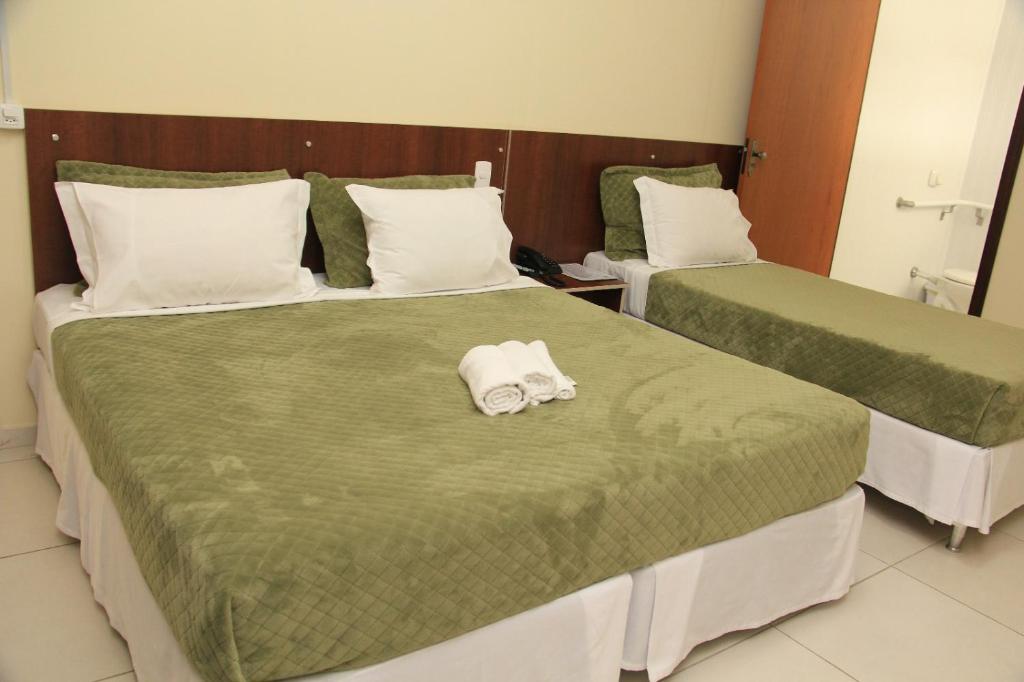 two beds in a hotel room with towels on them at Hotel Zandoná in Joinville