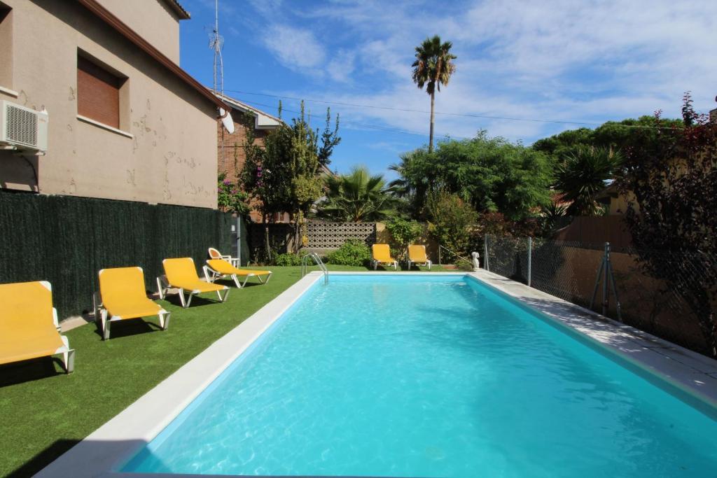 a swimming pool with yellow chairs next to a house at Pool and relax 20' from Barcelona in Premiá de Mar