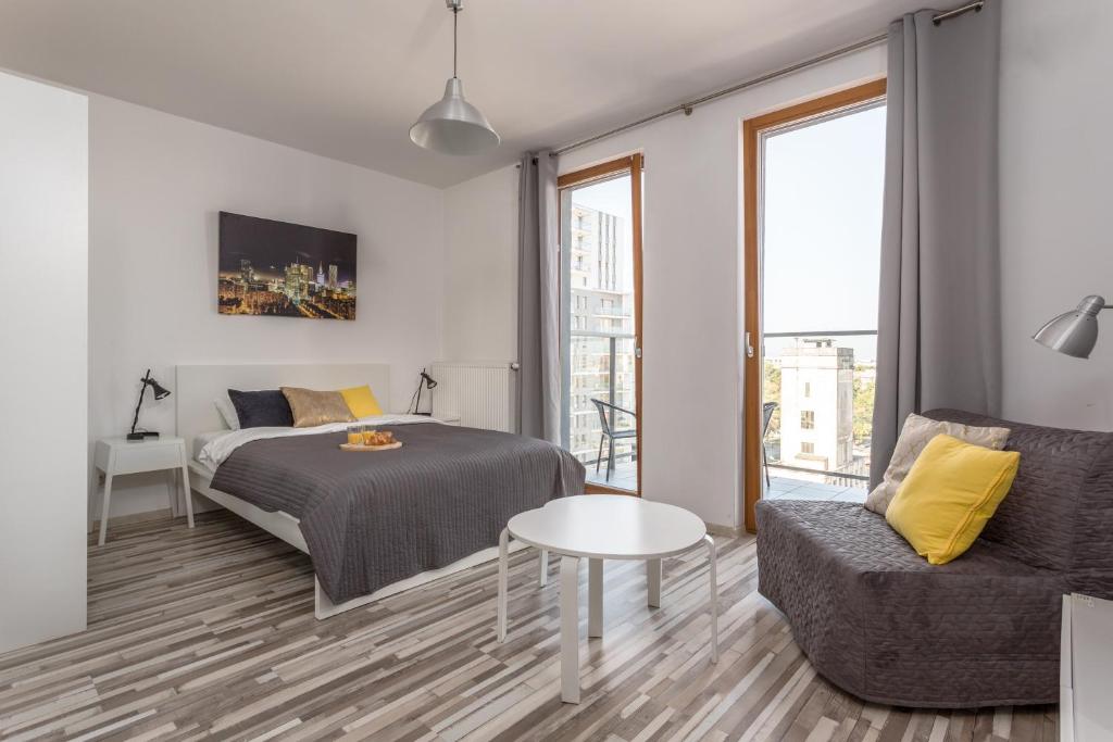 a bedroom with a bed and a couch and a table at Chill Apartments Wola Center in Warsaw