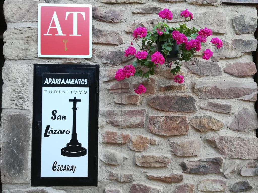 a sign on a brick wall with pink flowers at Apartamentos San Lázaro in Ezcaray