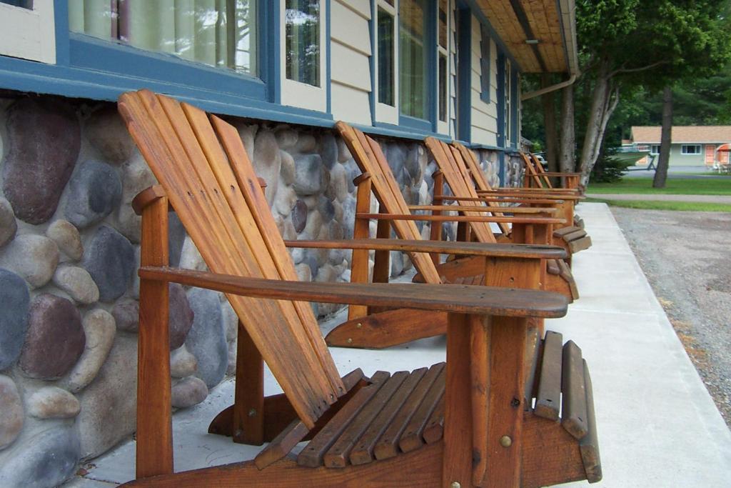 una fila de sillas de madera sentadas fuera de un edificio en Country Club Motel, en Old Forge