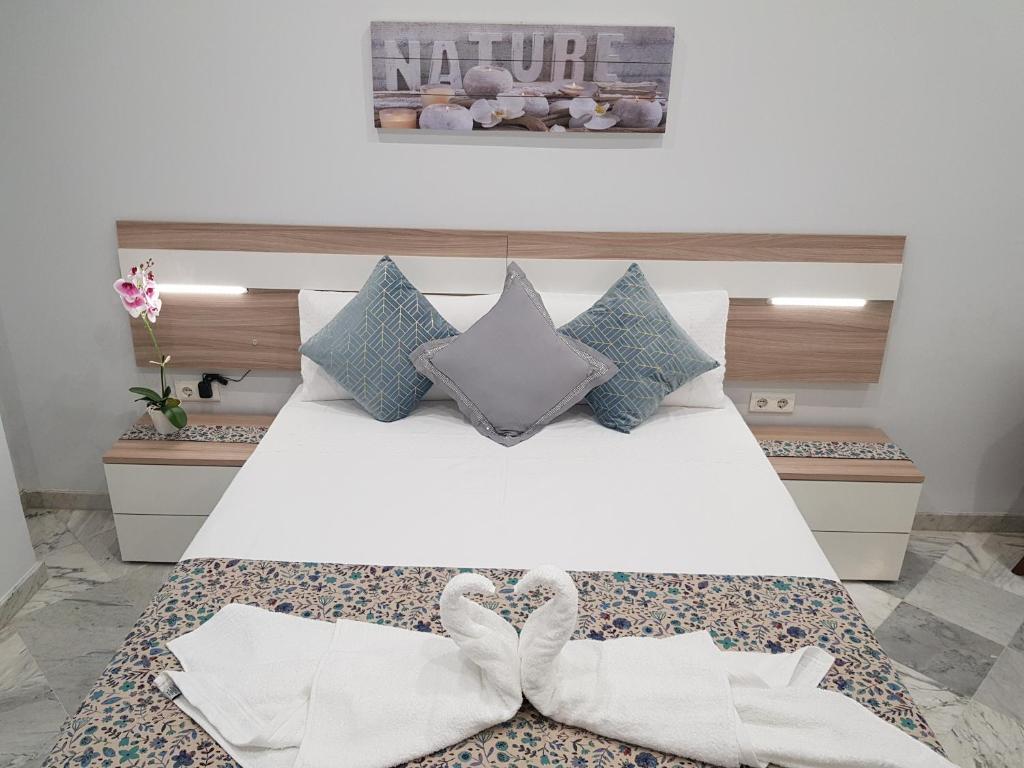 a bedroom with a white bed with two white bows at Apartamento Capuchinos Cordoba in Córdoba