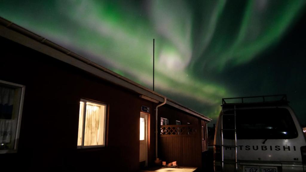 a truck parked in front of a house with the northern lights at Eldá Guesthouse in Myvatn