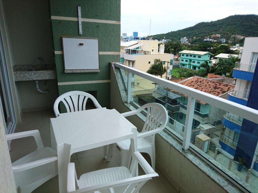 Un balcón con una mesa blanca y sillas en un edificio en Apto no centro de Bombinhas, en Bombinhas