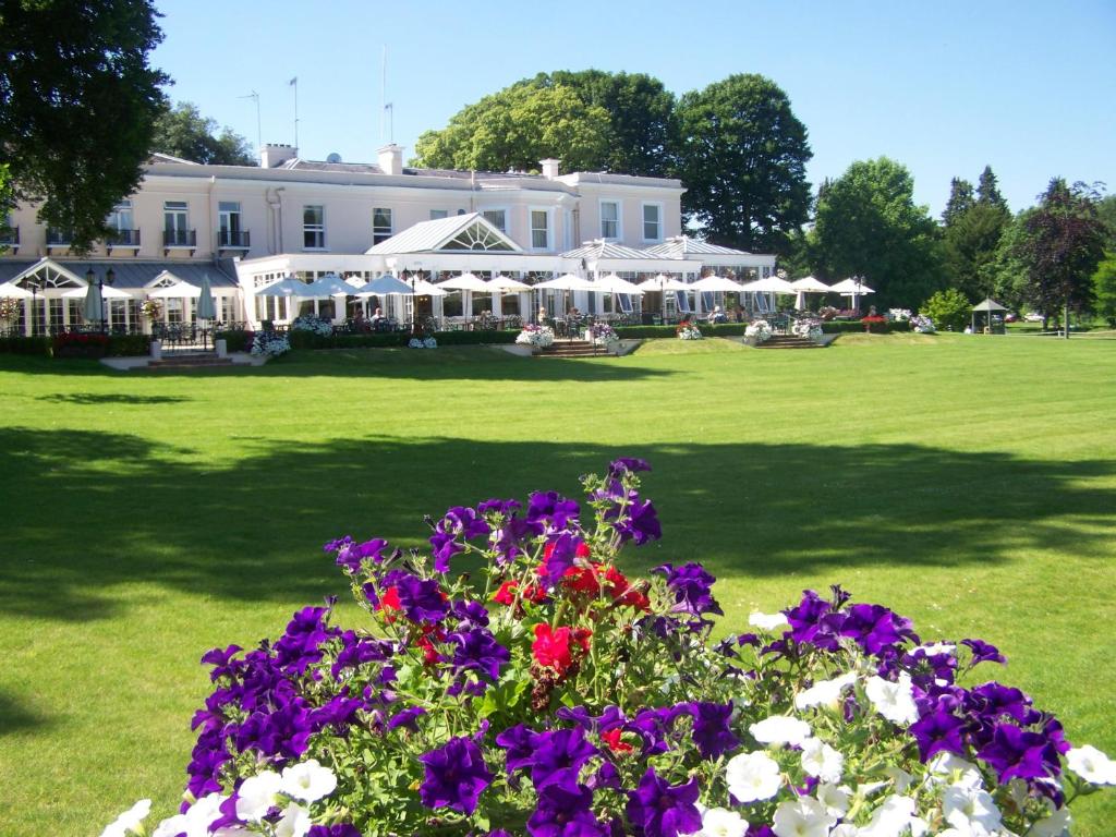 un grand bâtiment blanc avec des fleurs devant lui dans l'établissement Phyllis Court Members Club, à Henley-on-Thames