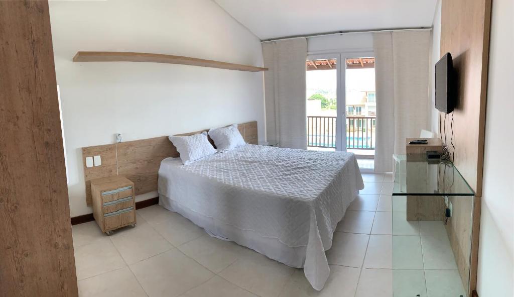ein Schlafzimmer mit einem Bett und einem TV in der Unterkunft Apartamento no Club Meridional in Praia dos Carneiros