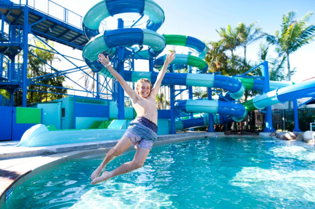 a young boy jumping off a water slide in a pool at Tasman Holiday Parks - North Star in Hastings Point