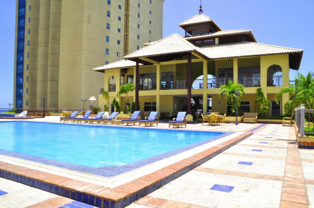 una piscina in un hotel con sedie e un edificio di Malecon Center a Santo Domingo