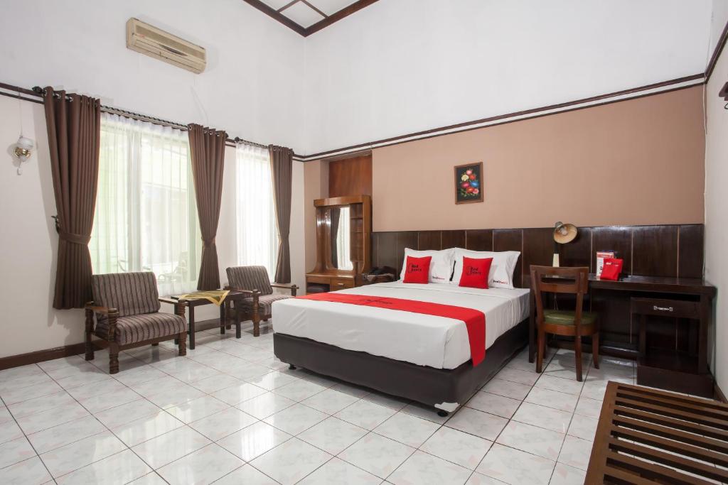 a hotel room with a bed and a desk and chairs at RedDoorz near Balai Kota Malang in Malang