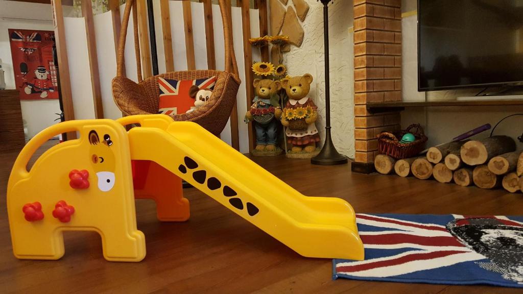 a yellow plastic slide on the floor of a living room at British Country Inn B&amp;B in Luodong