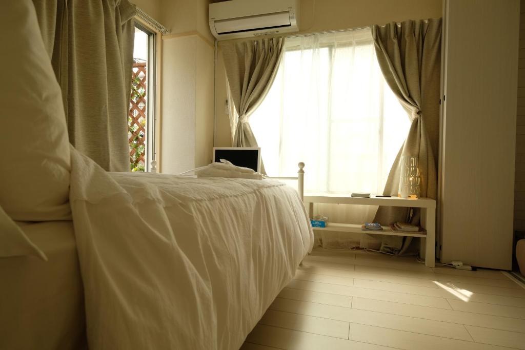 - une chambre avec un lit blanc et une fenêtre dans l'établissement COCO Nakameguro 201, à Tokyo