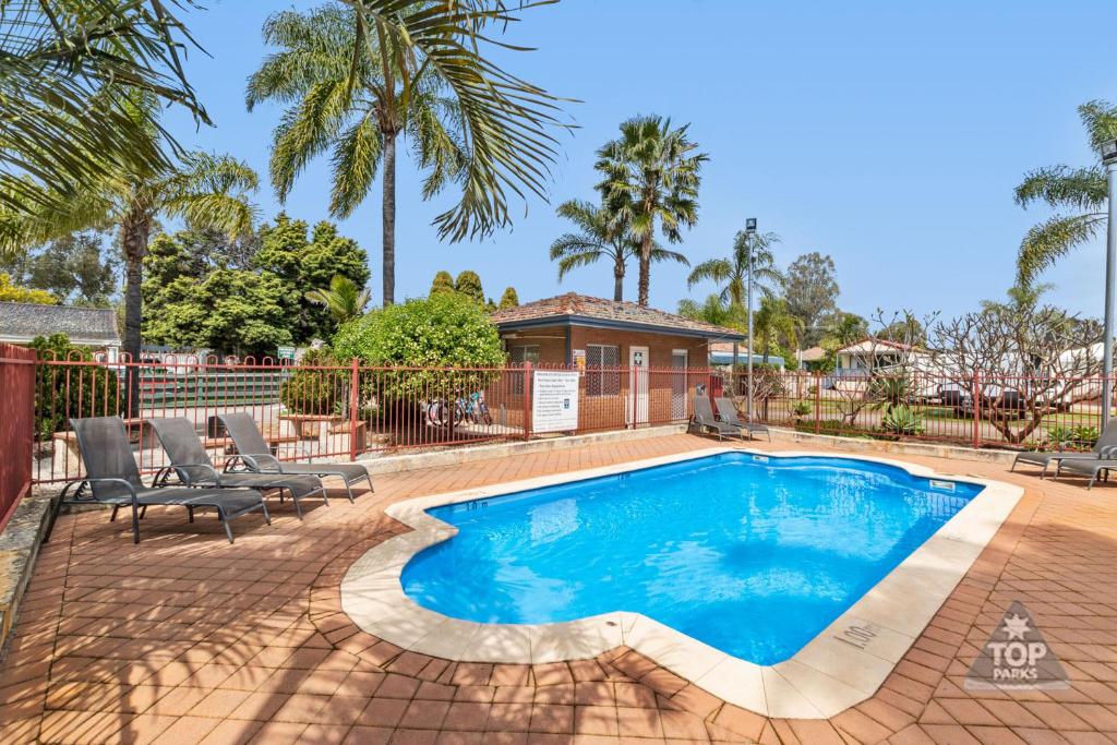 a swimming pool with chairs and a house at Central Caravan Park in Perth