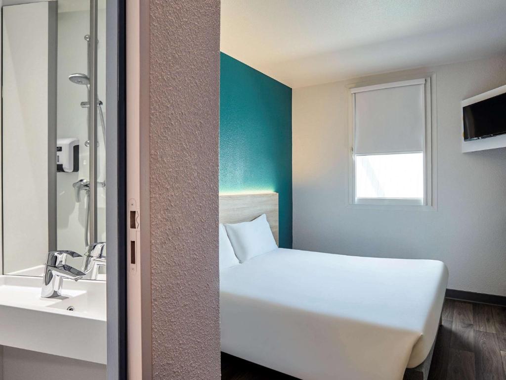 baño con cama blanca y lavamanos en hotelF1 Lyon Gerland Vénissieux, en Vénissieux