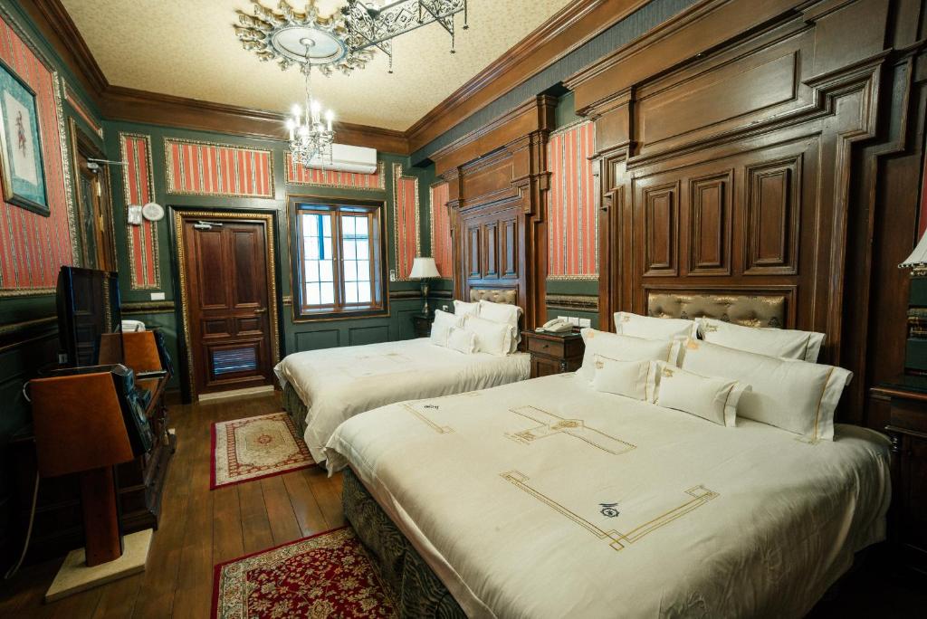 a hotel room with two beds and a chandelier at The Old England Manor in Ren&#39;ai