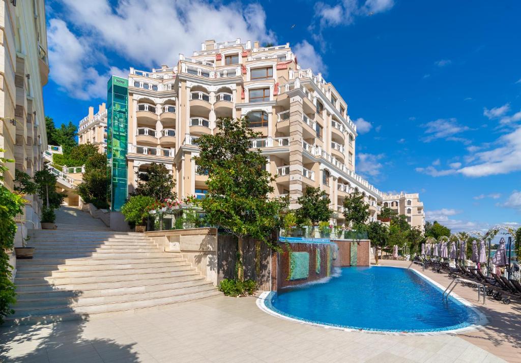 un bâtiment avec une piscine en face d'un bâtiment dans l'établissement La Mer Residence, aux Sables d'or