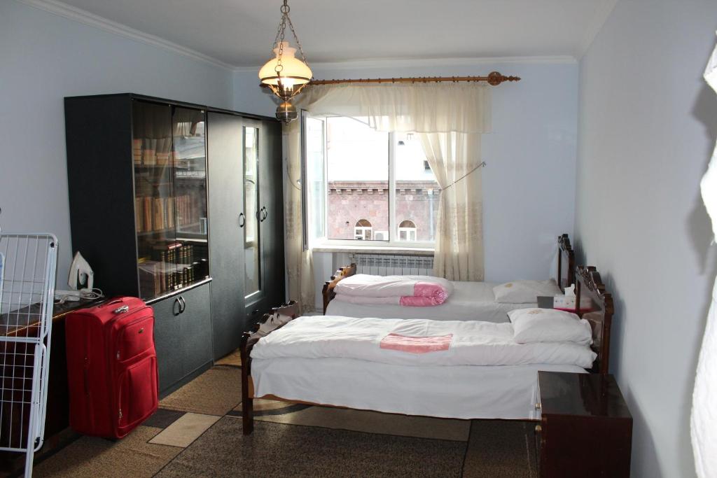 ein Schlafzimmer mit 2 Betten und ein Fenster mit einem roten Koffer in der Unterkunft Super Location in Yerevan