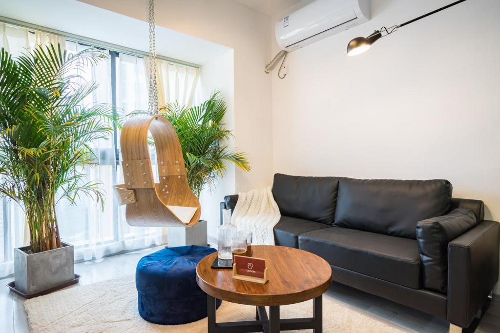 ein Wohnzimmer mit einem schwarzen Sofa und einem Tisch in der Unterkunft Chongqing Jiangbei·Guanyinqiao· Locals Apartment 00139090 in Chongqing