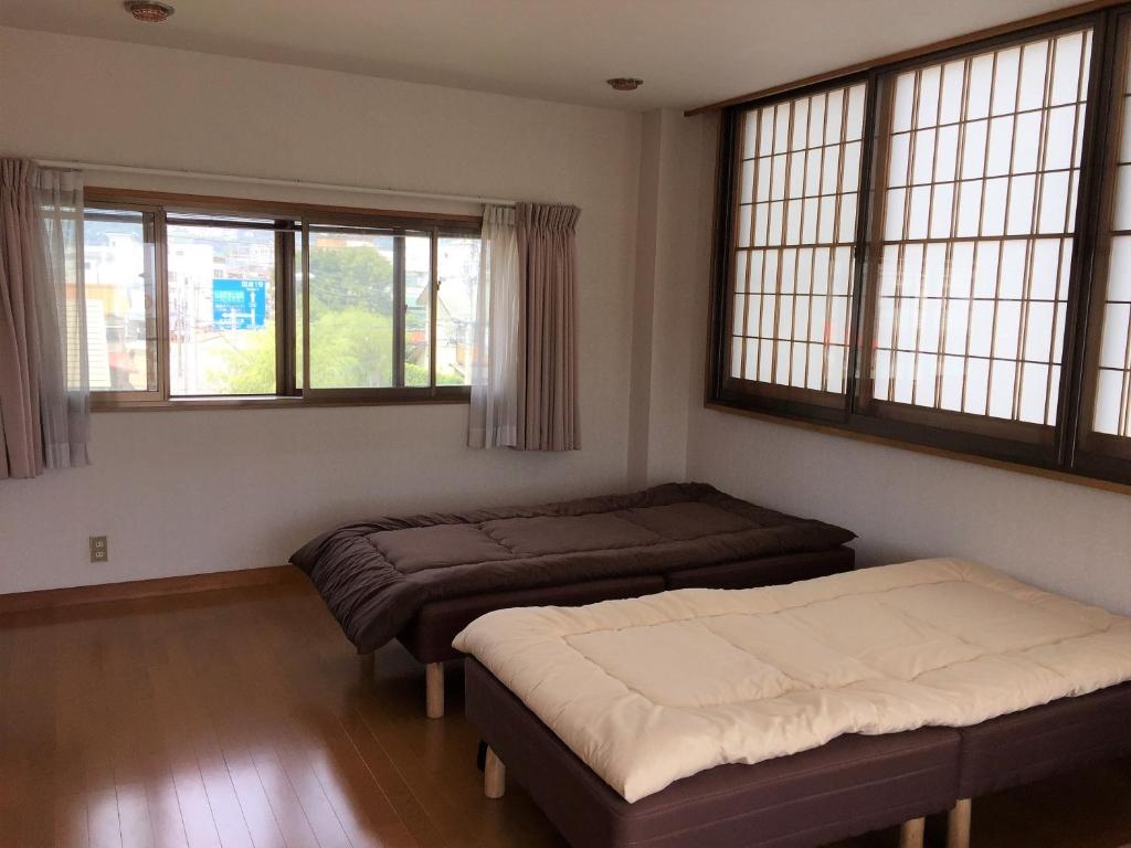 two beds in a room with two windows at Guesthouse LARGO in Odawara