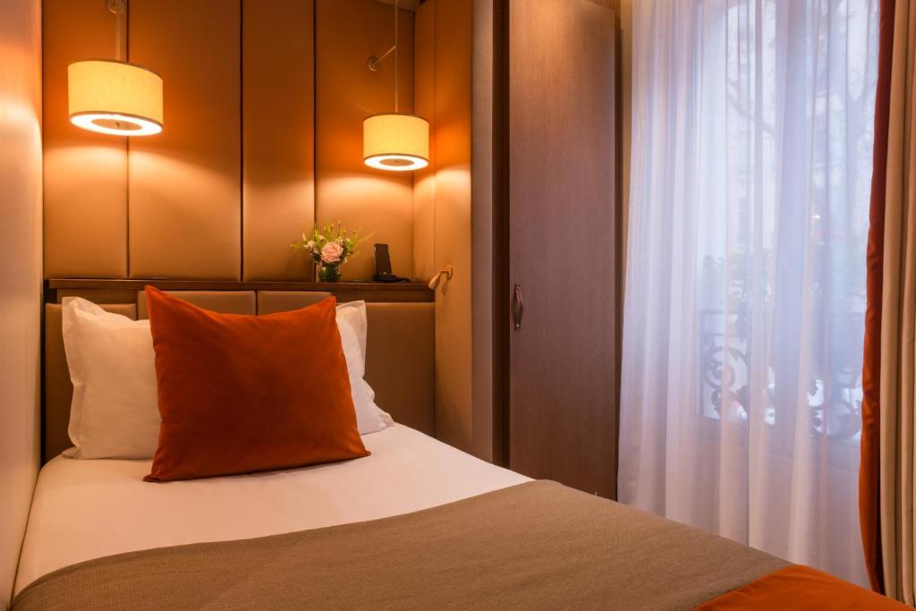 a bedroom with a bed with two lamps and a window at Hôtel La Bourdonnais by Inwood Hotels in Paris