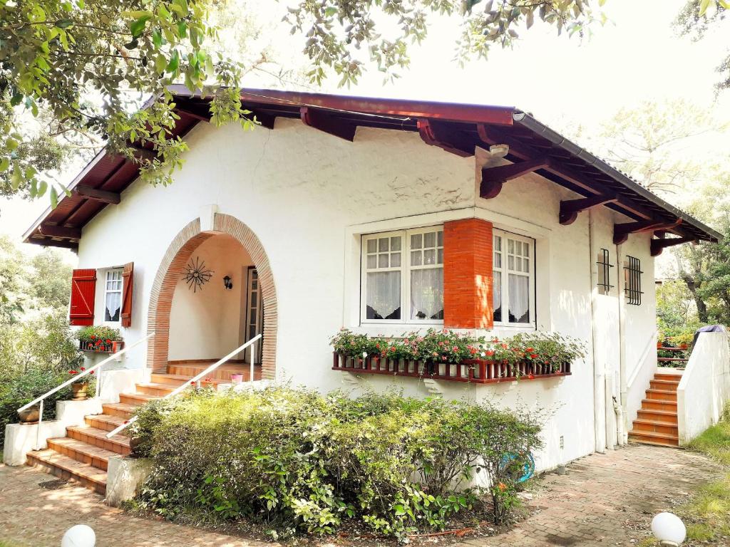 une maison blanche avec des fleurs dans une fenêtre dans l'établissement XAVIER 62 Maison Familiale 4 Chambres au Calme, à Pyla-sur-Mer