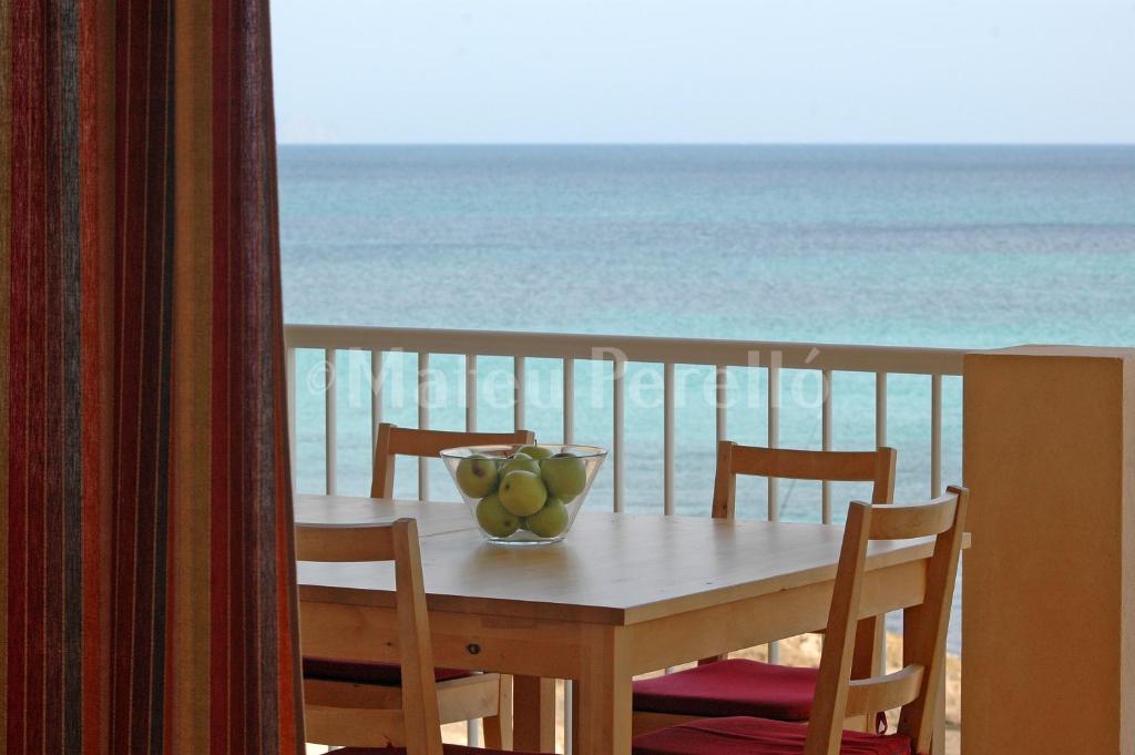 uma mesa com uma tigela de fruta numa varanda com o oceano em Casa Calma em Son Serra de Marina